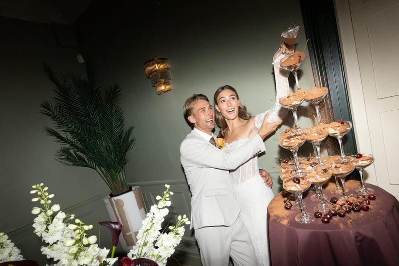 couple sprinkling cocoa powder on to a chocolate mousse tower