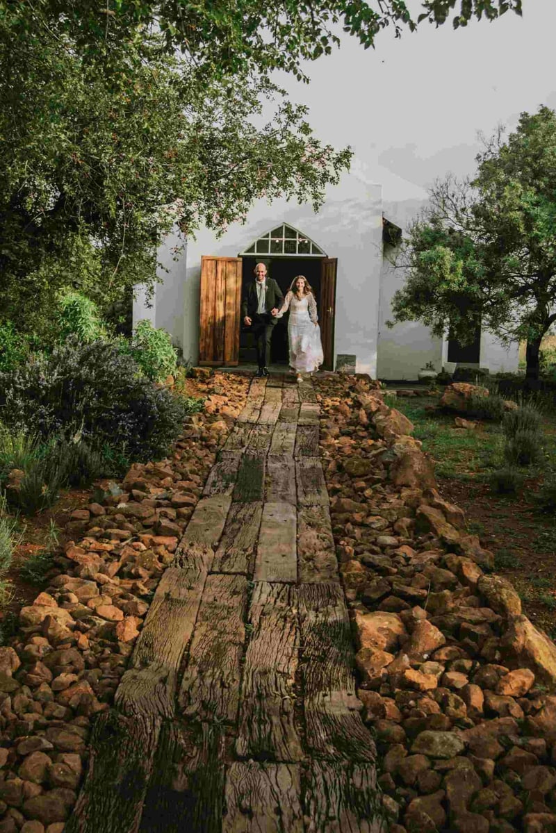A bride and groom about to walk down a wooden aisle at a rustic themed wedding
