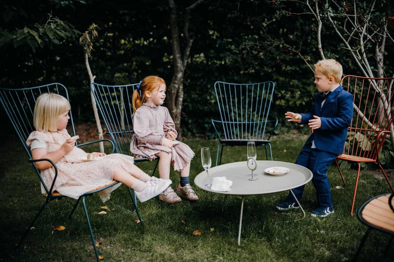 Children sitting down in chairs at a wedding outside
