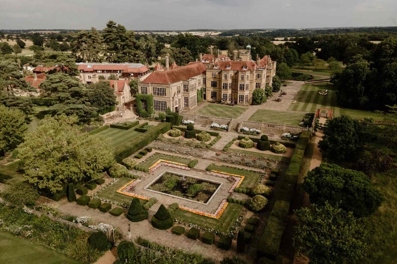 Aerial view of an Elizabethan country house wedding venue with formal parterre gardens and topiary hedging