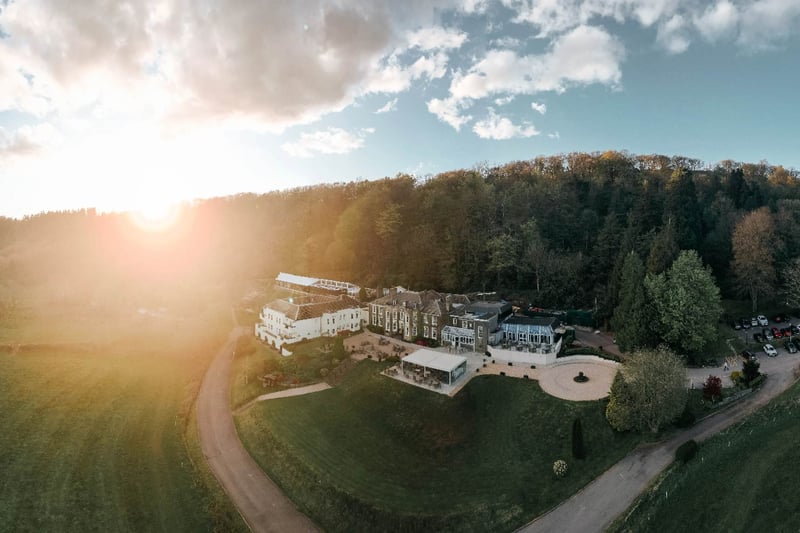 Aerial sunset view of a country house hotel wedding venue nestled in autumn woodland