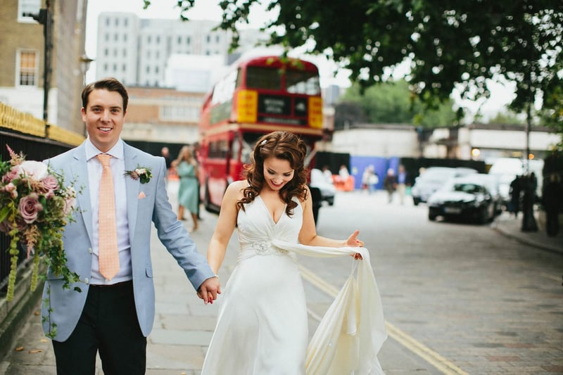 Bride and groom smiling at a london wedding with a red double decker london bus visibie in the background