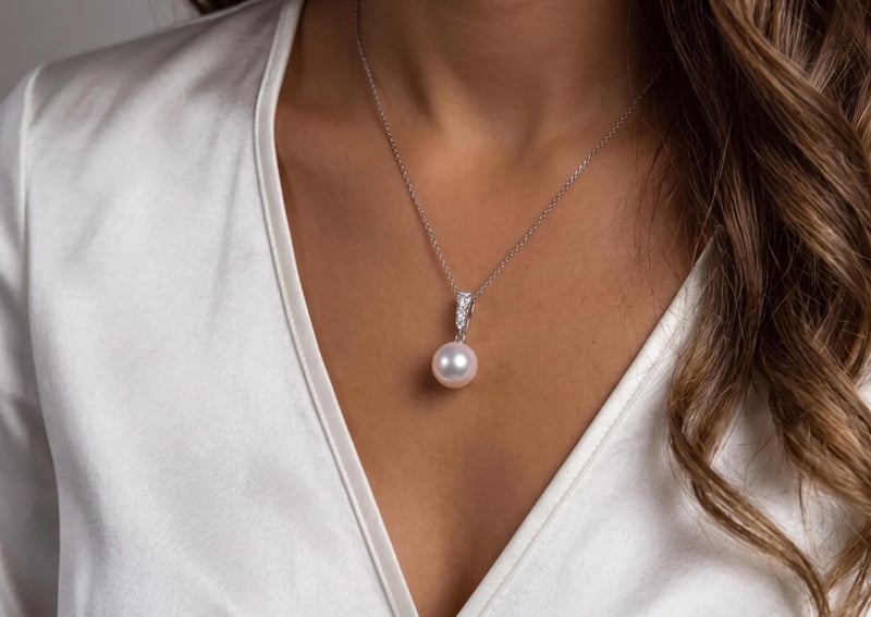 Woman wearing a pearl pendant necklace with a diamond clasp on silver chain
