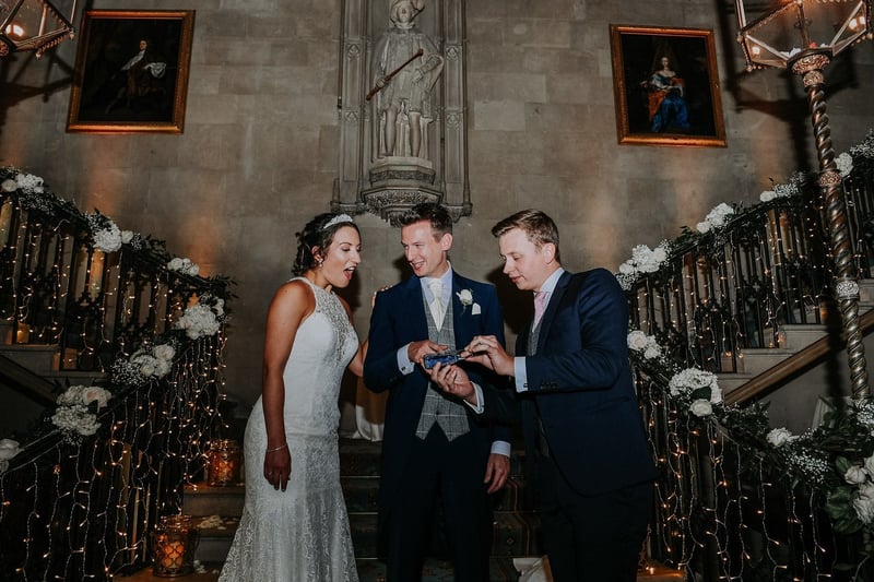 a wedding magician performs a trick for a bride and groom on a staircase.