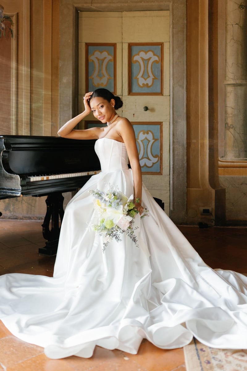a bride posing with her bouquet next to a grand piano.
