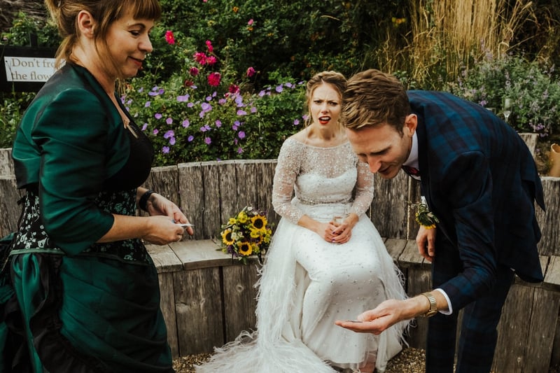 a female magician performs a trick to a stunned bride and groom.