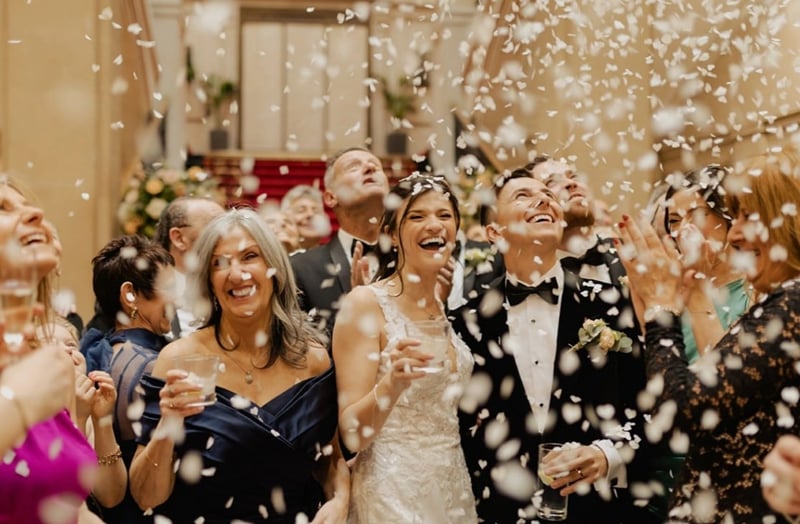 mother of the bride pictured with the couple surrounded by confetti