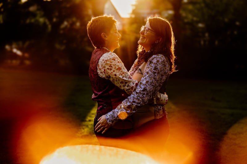 a lgbtq+ couple smile at each other in a golden hour photo.