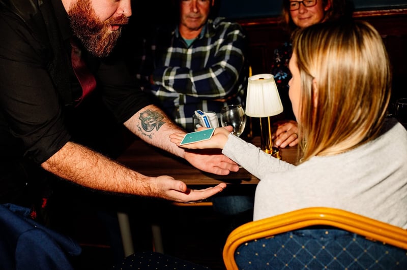 a magician performs a card trick to seated guests.