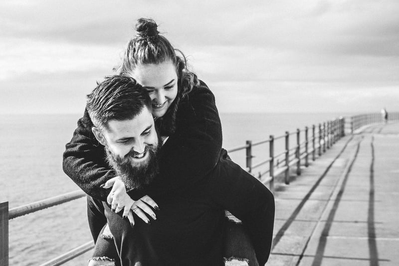 a man gives a woman a piggy back along the sea front.