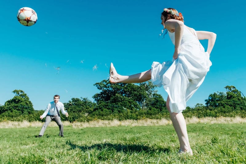 Bride kicking a football to the groom