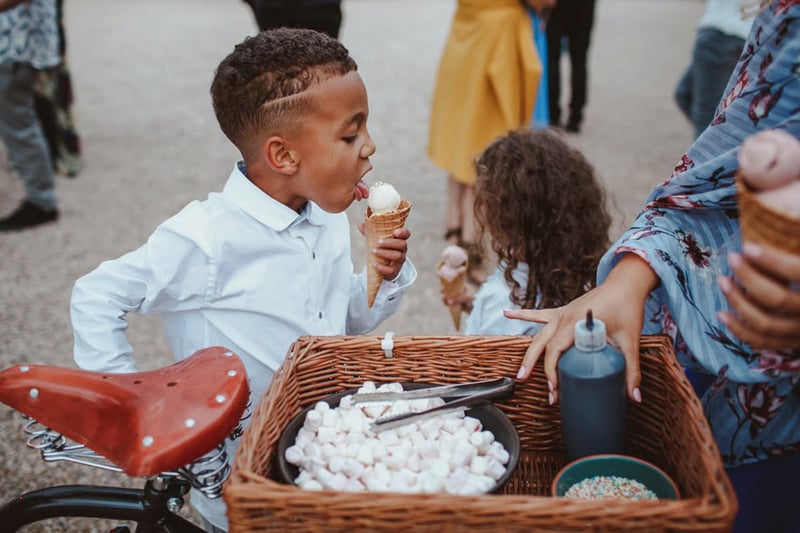 Little kid licking an ice cream from a cart at a wedding