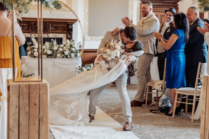 a bride and groom enjoying a dramatic first kiss at their wedding ceremony.
