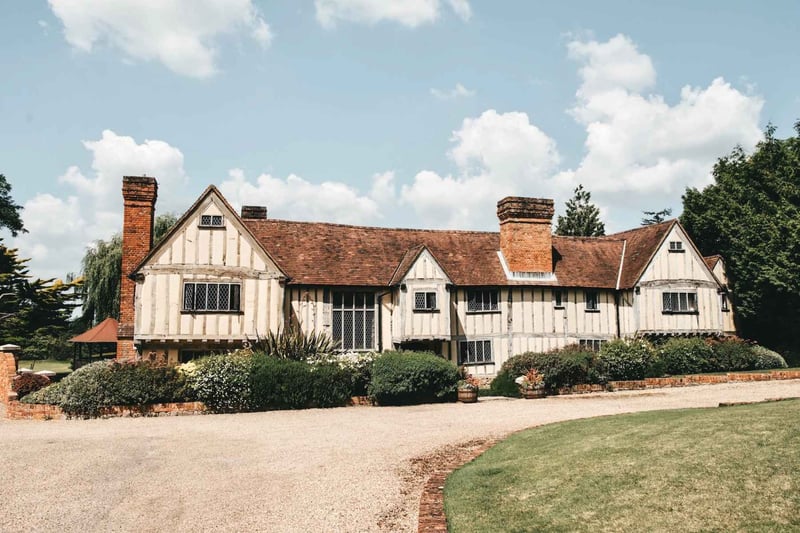 Exterior of a timber-framed Tudor hall wedding venue with brick chimneys and gravel driveway