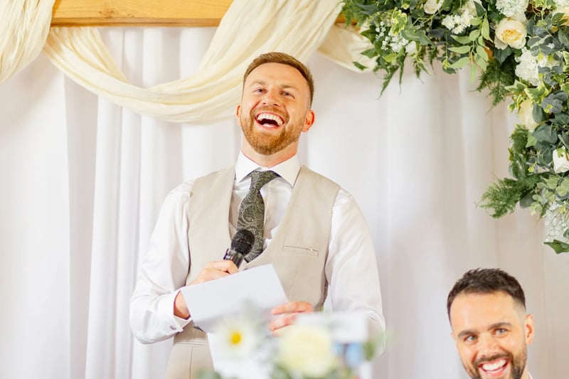 Best man laughing as he gives a speech