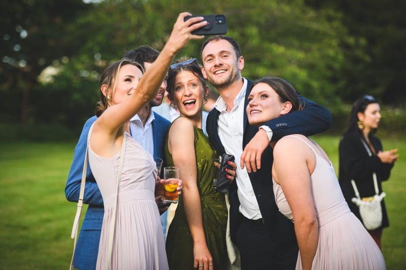 a group of wedding guests take a selfie.