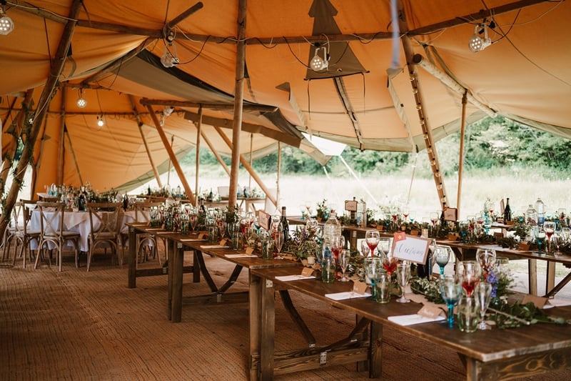 interior of a tipi wedding tent with long tables set up for a wedding breakfast.