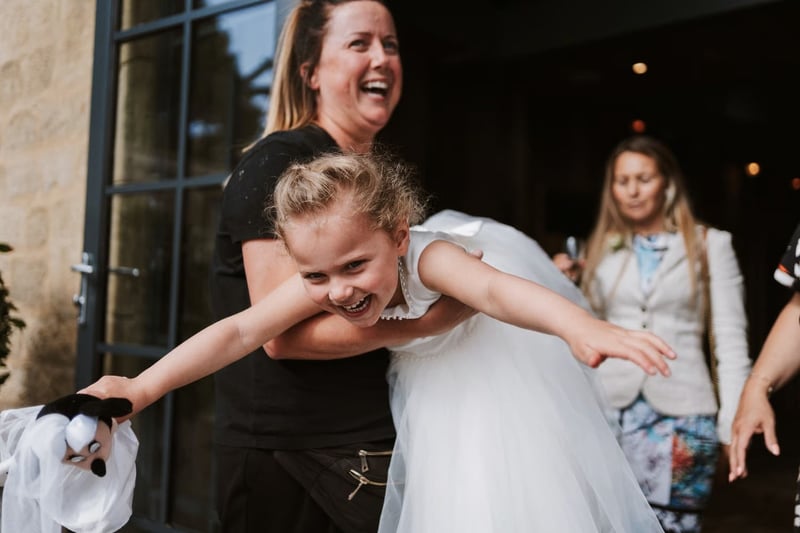 Wedding nanny lifting a flower girl as she laughs