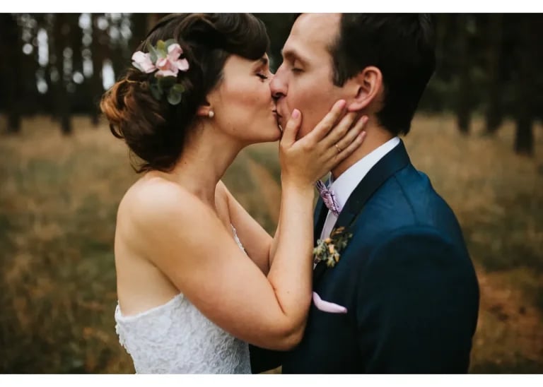 Braut und Bräutigam küssen sich bei einem romantischen Hochzeitsshooting im Wald