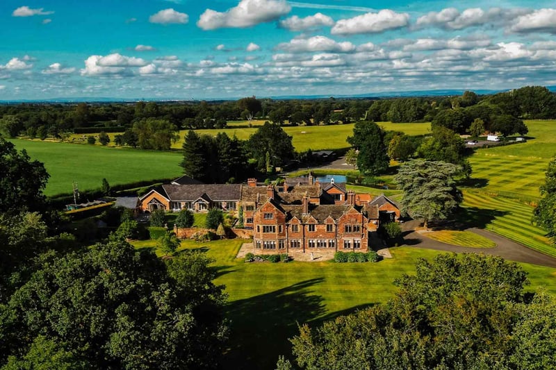 Aerial view of a red-brick Victorian country house wedding venue surrounded by manicured lawns and English countryside