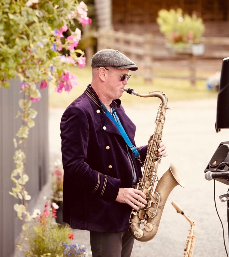 a male wedding saxophonist performs outdoors.