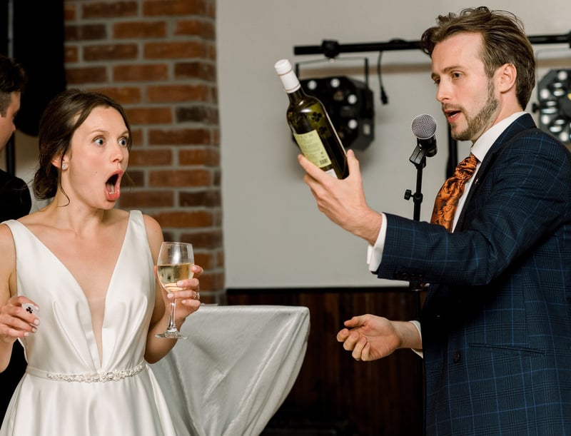 a bride looks stunned as a wedding magician holds a bottle of wine and performs his trick.