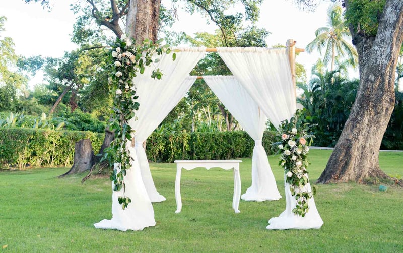 Romantic white curtained wedding arch set up at a garden wedding in canada