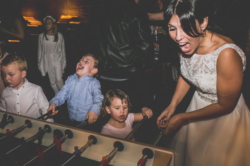 Bride playing on a mini football table with young guests