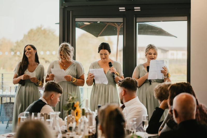 Four bridesmaids in sage green dresses giving a speech together