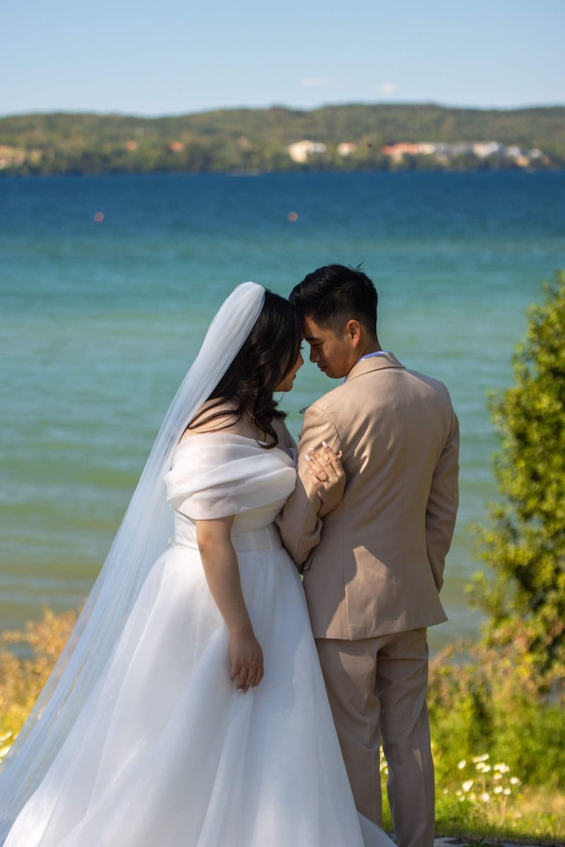 Bride and groom touching their foreheads together next to a lake in canada