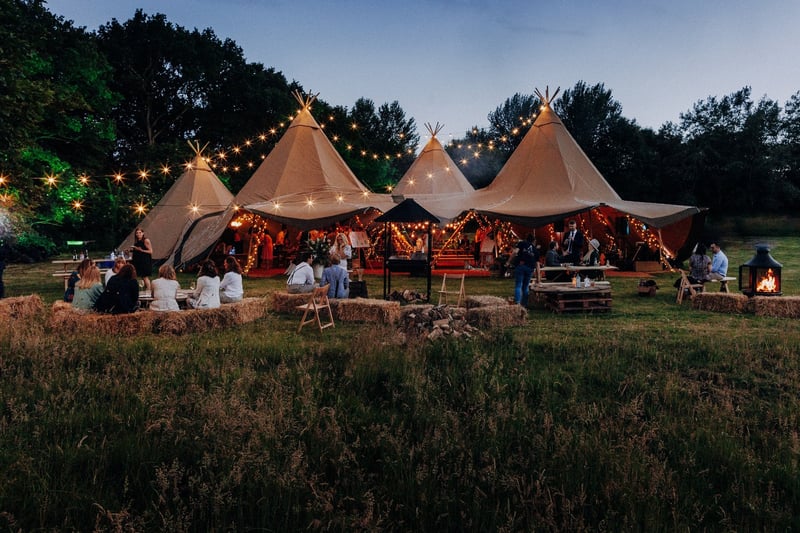exterior of a wedding tipi tent in the evening as guests enjoy the outdoor space.