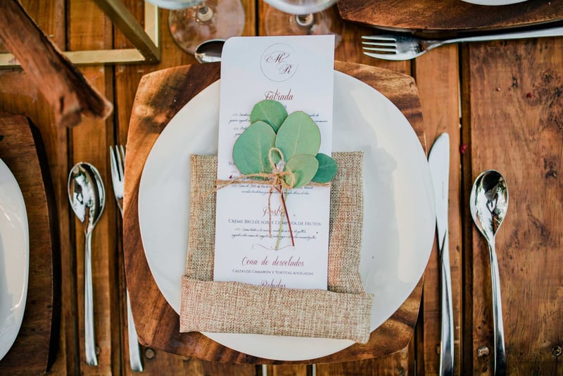 An eco friendly wedding place wedding with a burlap napkin and greenery