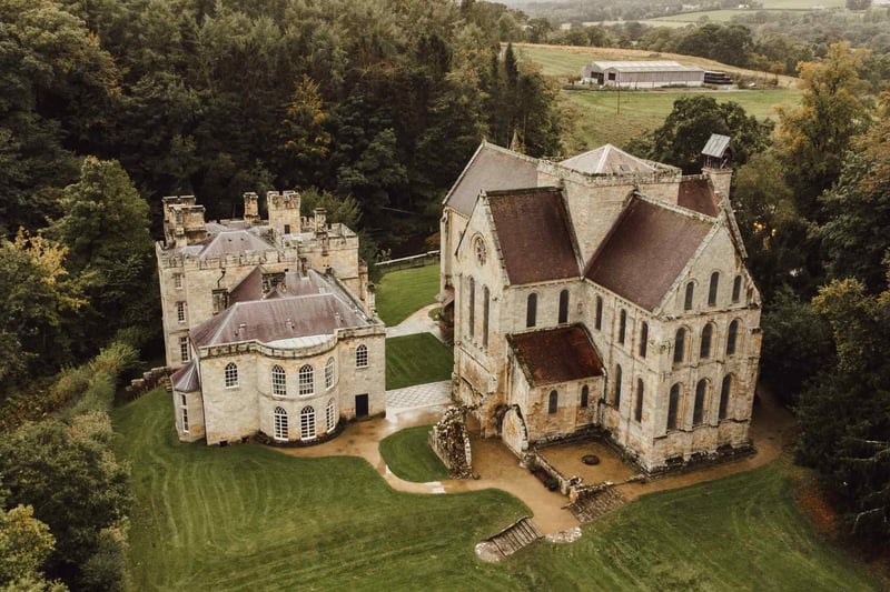 Aerial view of a medieval castle and ruined chapel wedding venue nestled in woodland
