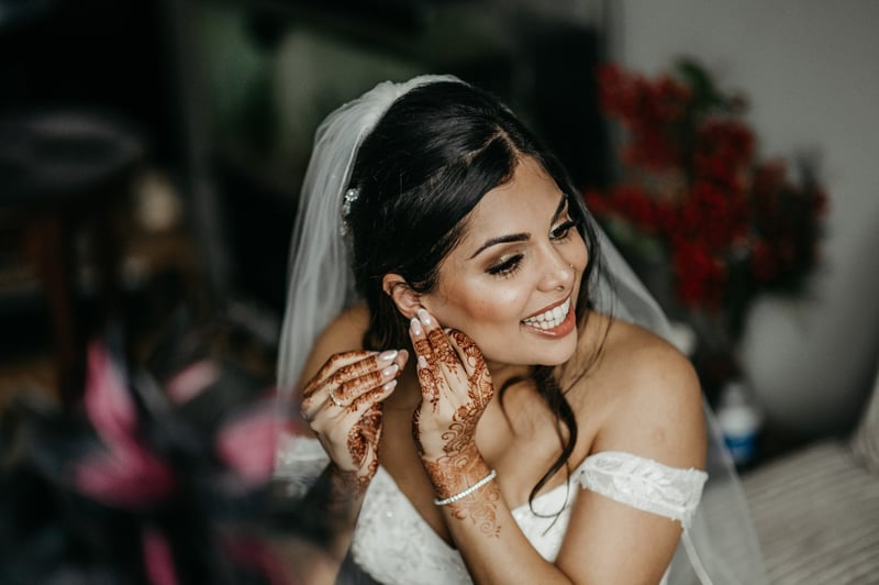 a Hindu bride putting in her earrings as she gets ready for her wedding.