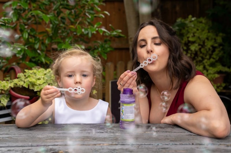 a young woman and girl blowing bubbles together