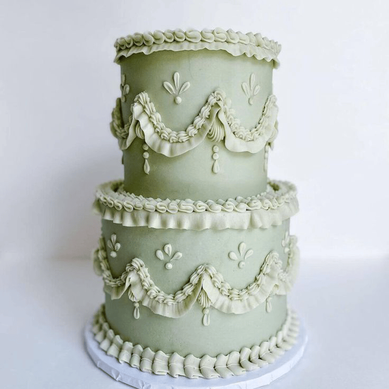 a two-tier Lambeth-style wedding cake in a matcha green hue.
