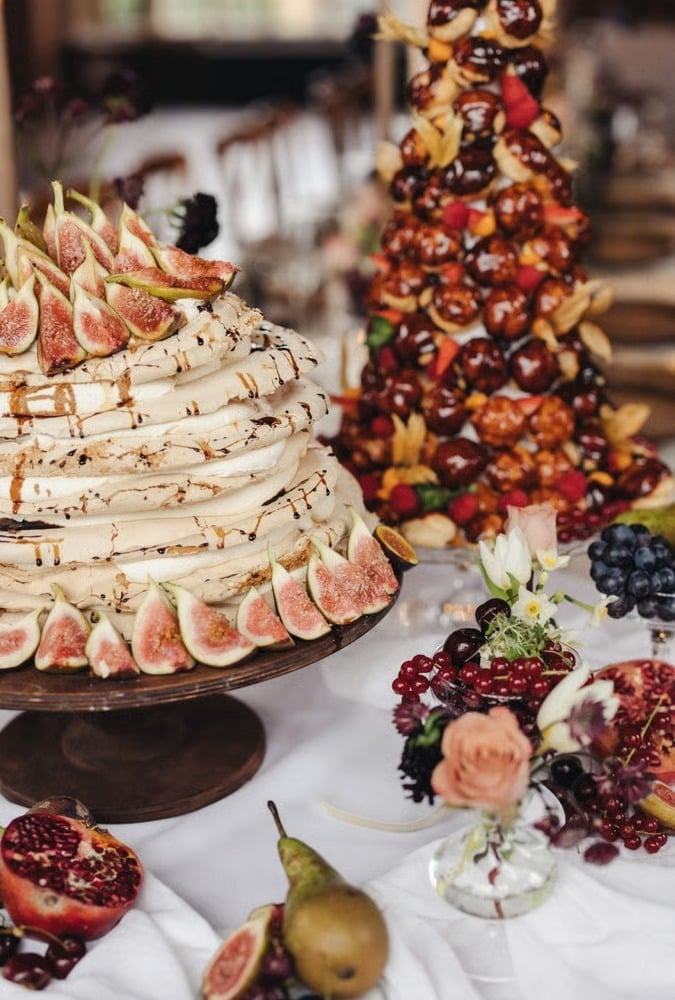 A meringue stack wedding cake with figs next to a croquembouche