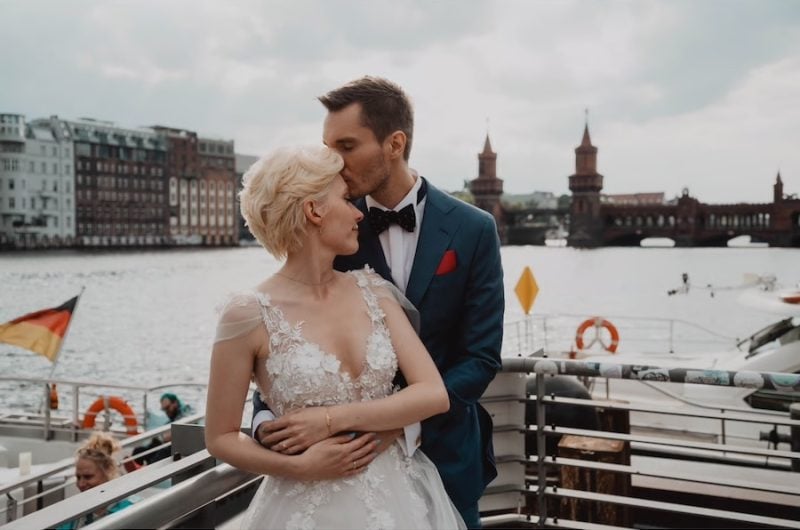 Hochzeitspaar vor einem Fluss mit Brücke im Hintergrund