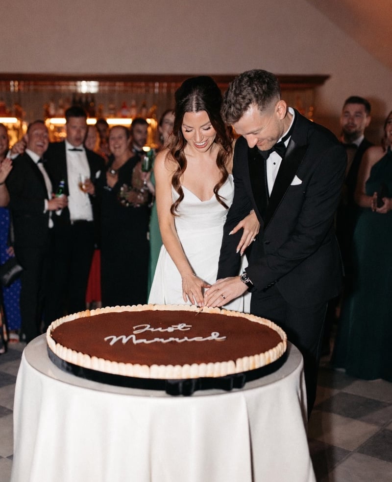 a bride and groom cutting into a large tiramisu that reads 'just married'