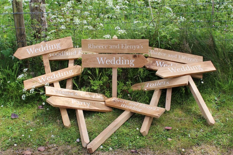 A stack of wooden wedding signs lying in a pile on a green meadow