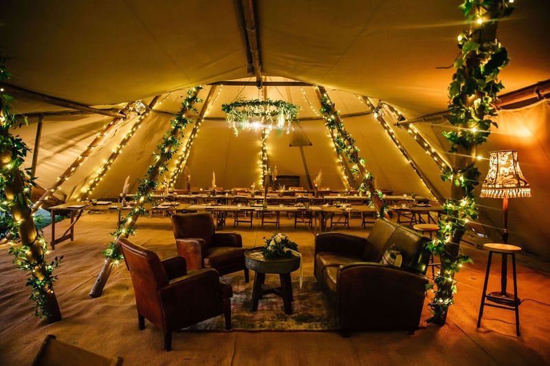 interior of a tipi wedding tent featuring cosy lighting, leather sofas and rugs.
