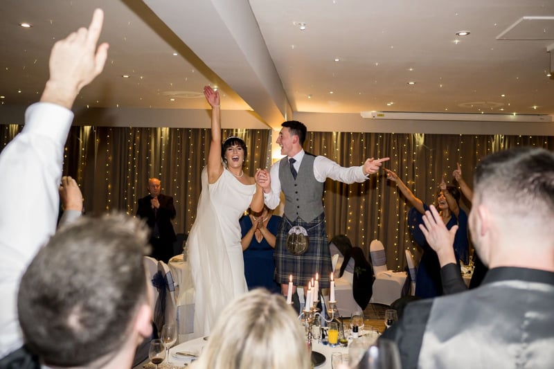Bride and groom excitedly being introduced to their wedding reception