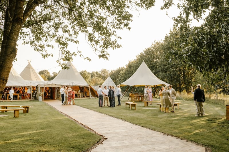 wedding guests gather outside a group of tipi wedding tents.