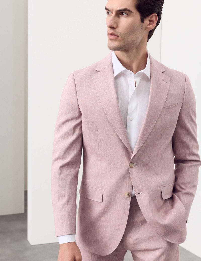 a male model wearing a dusky pink suit with a white shirt.