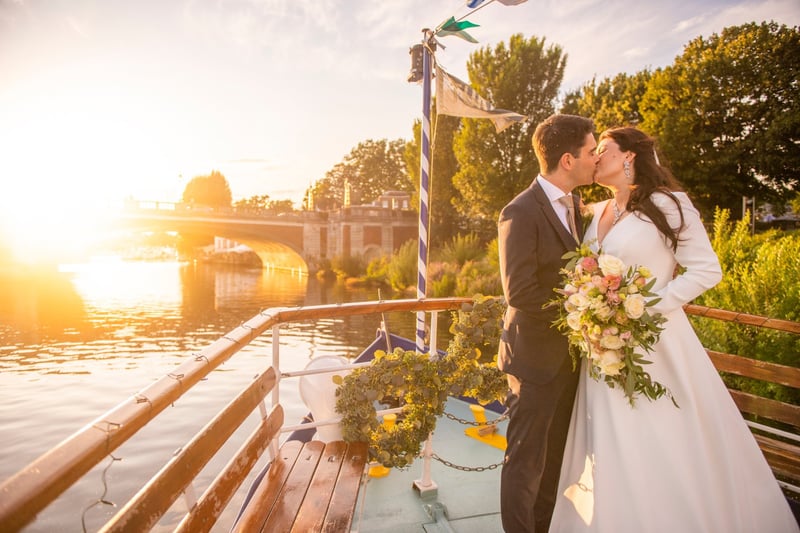 a bride and groom kiss at golden hour on a boat.