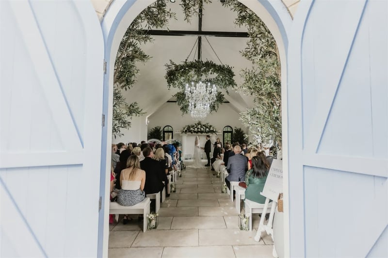 View into a wedding ceremony chapel decorated with greenery through pale blue doors