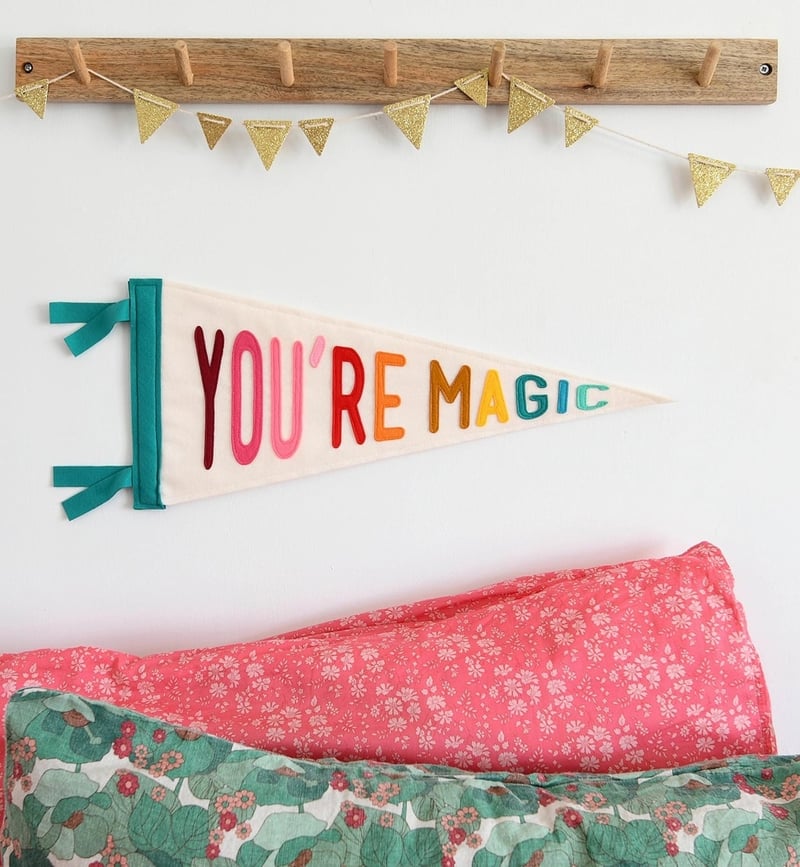 a pennat flag that reads, 'you're magic' in colourful lettering on a child's bedroom wall.