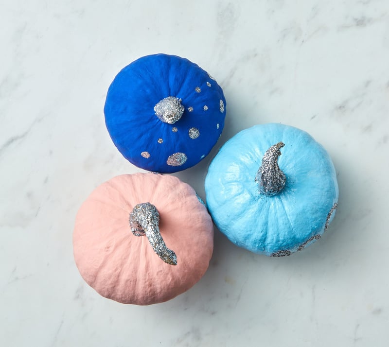 a trio of painted pumpkins in pink, dark blue and pale blue.
