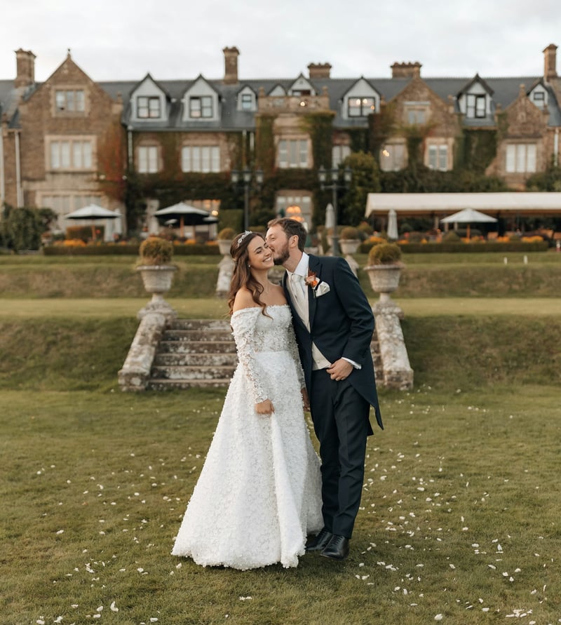 a bride and groom kissing in front of their country house wedding venue. the groom is wearing a morning suit.