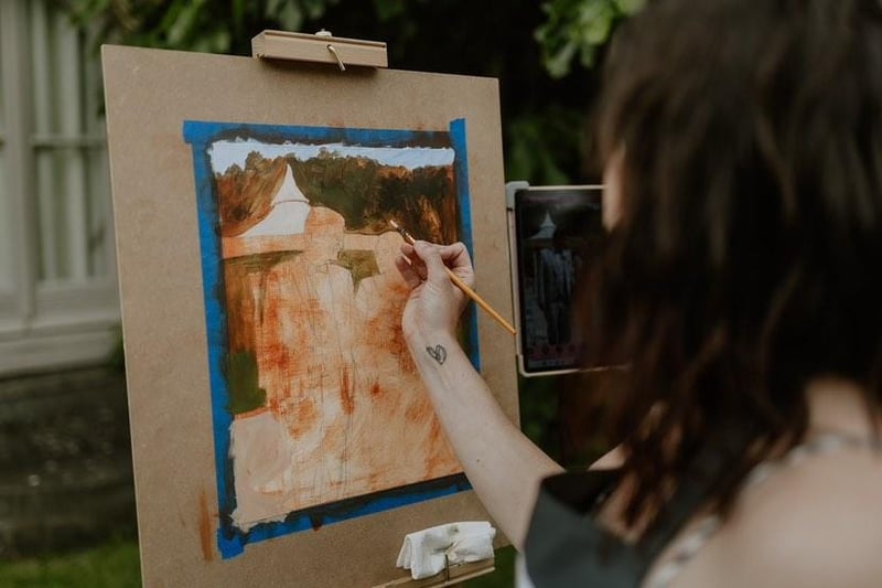 a live wedding painter paints during the wedding breakfast.